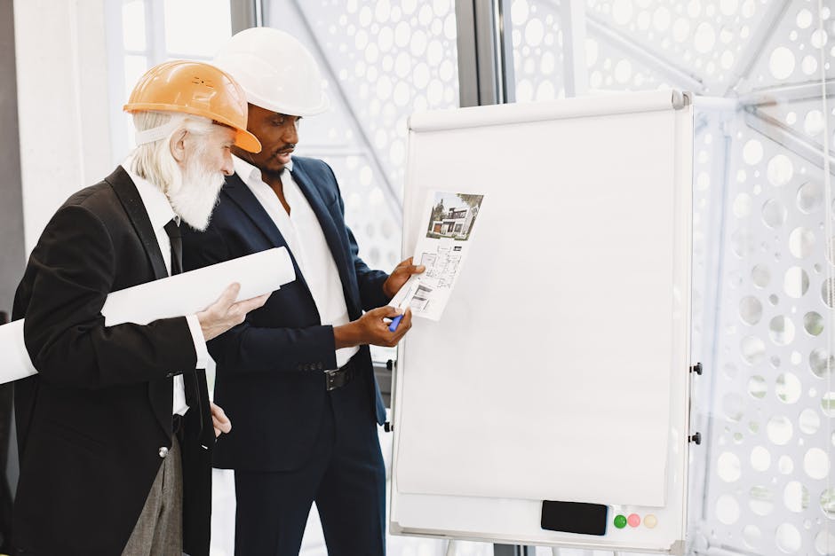 Two architects discussing building plans with hard hats and blueprints indoors.